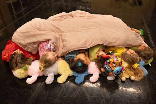 Tanssijoiden päälaet näkyvät suuren beigen värisen peiton alta.