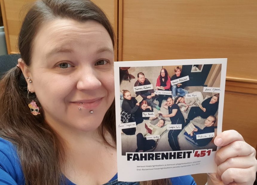 Hymyilevä nainen, jolla on kädessään Fahrenheit 451 -käsiohjelma.